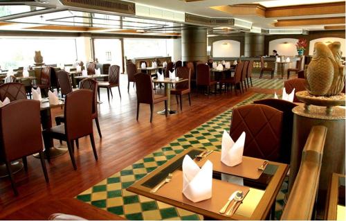 una sala da pranzo con tavoli e sedie in un ristorante di Suntara Wellness Resort & Hotel a Chachoengsao