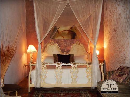 um quarto com uma cama de dossel branca com cortinas em Hotel Torres Del Fuerte em El Fuerte