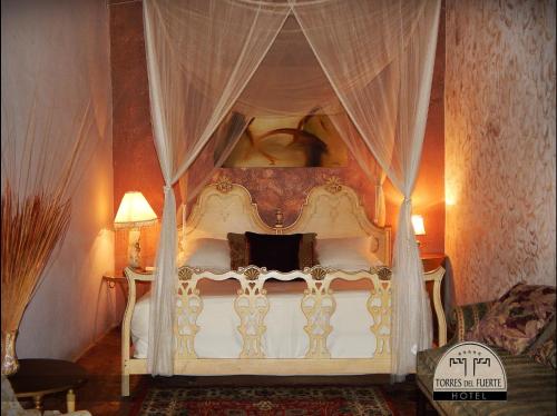 a bedroom with a white canopy bed with curtains at Hotel Torres Del Fuerte in El Fuerte