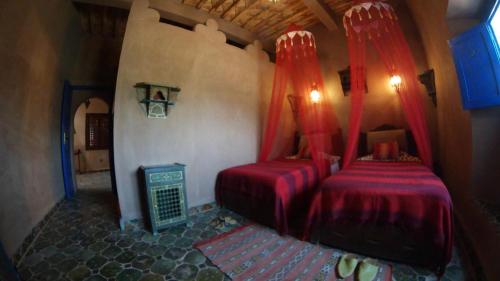 een slaapkamer met 2 bedden en rode gordijnen bij Le Sauvage Noble in Zagora