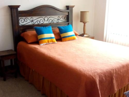 Una cama con almohadas azules y amarillas. en Habitaciones Eco-Terrazas, en Guatemala