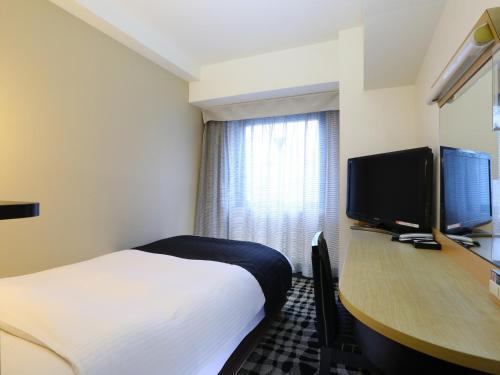a hotel room with a bed and a desk with a television at APA Hotel Ikebukuro Eki Kitaguchi in Tokyo
