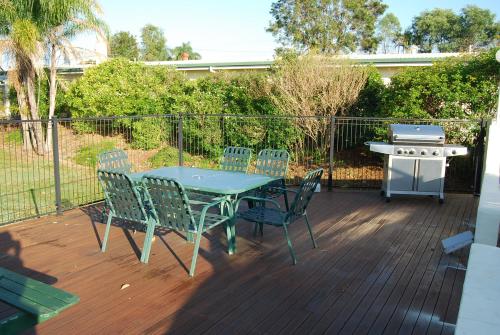 einen Tisch und Stühle auf einer Terrasse mit Grill in der Unterkunft Avocado Motor Inn in Childers
