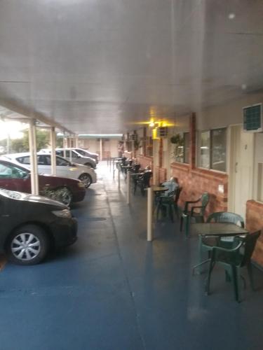a restaurant with tables, chairs, and umbrellas at Avocado Motor Inn in Childers