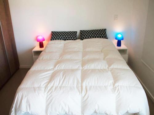1 dormitorio con 1 cama blanca y 2 lámparas en El más cool de la península. Gala Puerto., en Punta del Este