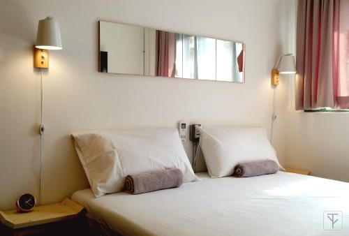 a bedroom with a white bed with a mirror on the wall at T-Boutique Hostel - Hua Lamphong in Bangkok