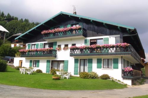 una casa con flores en los balcones y mesas en Chalet Fleur des Alpes en Les Gets