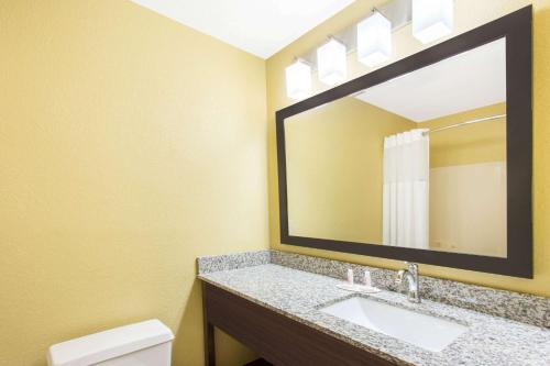 a bathroom with a sink and a mirror at Days Inn & Suites by Wyndham Davenport East in Davenport