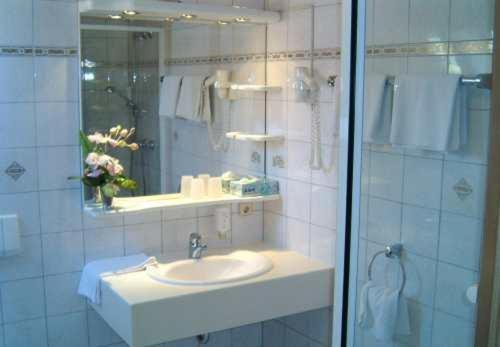 uma casa de banho com um lavatório, um espelho e um chuveiro em Landhotel Krone em Königsbach Stein