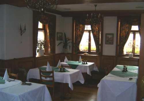 a dining room with white tables and chairs and windows at Landhotel Krone in Königsbach Stein