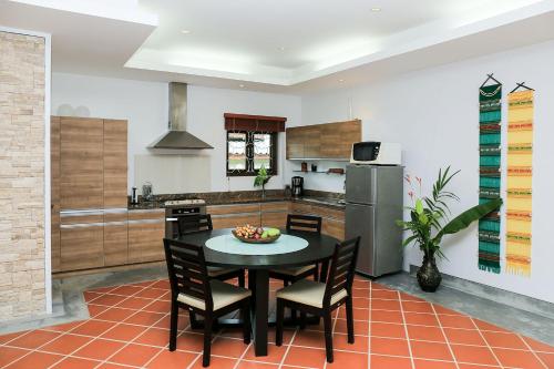 a kitchen with a table and chairs in a kitchen at Sabai Private Pool Villa Khao Lak in Khao Lak