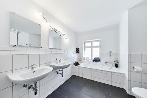 La salle de bains blanche est pourvue de 2 lavabos et d'une baignoire. dans l'établissement Wohnung 5 - nur 5-10 min vom Europapark, à Ettenheim