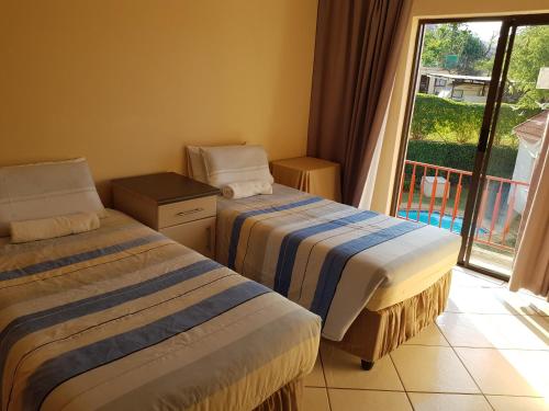 a hotel room with two beds and a balcony at Ezulwini Guest House in Ezulwini