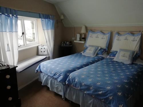 Schlafzimmer mit einem Bett mit blauer Bettwäsche und einem Fenster in der Unterkunft The House on the Props in Polperro