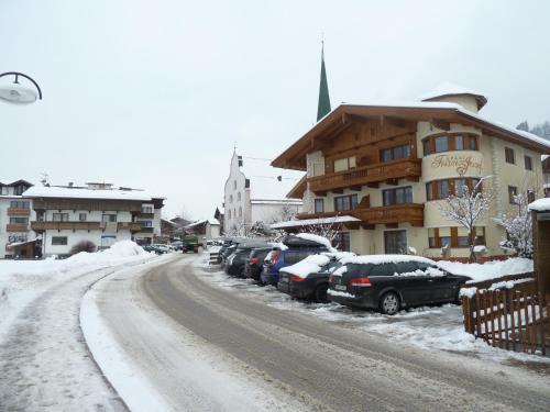 a snow covered street with cars parked next to a building at Apart Franz Josef in Stumm