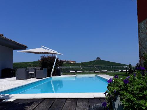 a swimming pool with a table and an umbrella at Red Wine Camere in La Morra