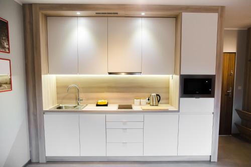 a kitchen with white cabinets and a sink at ULMA apartment in Wieliczka
