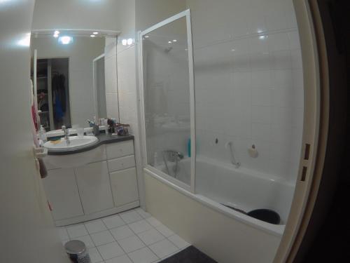 une salle de bain blanche avec une douche et un lavabo dans l'établissement Allées d'Etigny T1Bis 41 m2 1 chambre 4 couchages 200 m de la Crémaillère Express 400 m des Thermes, à Luchon