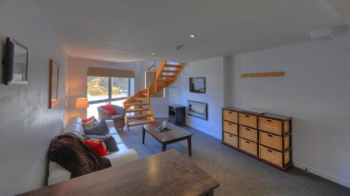 a living room with a staircase and a couch at Snowgoose Apartments in Thredbo