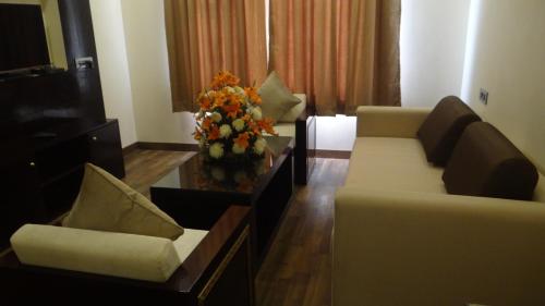 a living room with two couches and a vase of flowers at The Legend in Allahābād