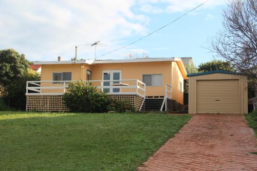 a yellow house with a gate and a garage at Brandis Beach House in Guilderton