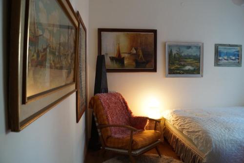 a bedroom with a bed and a chair and pictures on the wall at Goldy Suite in Haifa