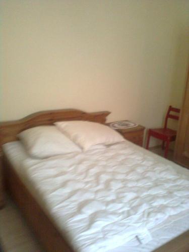 una camera da letto con un letto con lenzuola bianche e una sedia di Gasthof Weingut Brand Walter a Hörbing