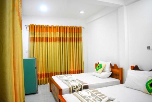 a bedroom with two beds and a yellow curtain at Herbage Natural Ella in Ella