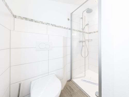a white bathroom with a shower and a toilet at Haus Leo in Cuxhaven