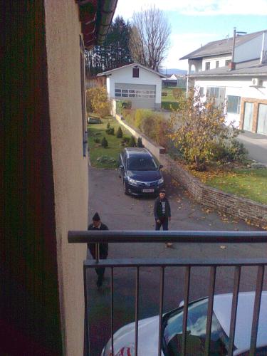 dos hombres parados en un balcón mirando a un coche en Gasthof Weingut Brand Walter, en Hörbing