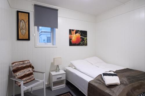 a small bedroom with a bed and a chair at Kristina Apartment & Alma House in Andenes