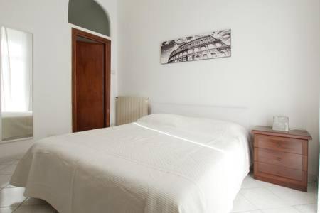 a bedroom with a white bed and a wooden dresser at Roma Ostia 100 mt sea in Lido di Ostia