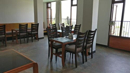 uma sala de jantar com mesa, cadeiras e janelas em Hotel Ninamma em Gangtok