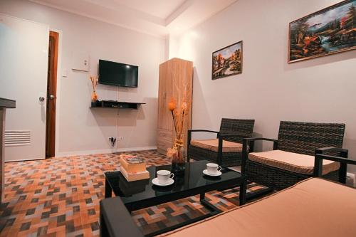 a living room with a table and chairs and a television at Kingswick Residences & Lodge in Dumaguete