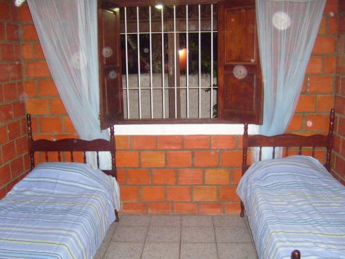 two beds in a room with a window at Casa de Arlete in Barra do Gil
