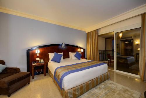 a bedroom with a bed and a couch and a chair at Stella Di Mare Beach Hotel & Spa in Sharm El Sheikh