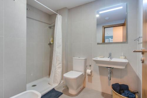 a white bathroom with a toilet and a sink at Surfer's Beach Apartment in La Tejita