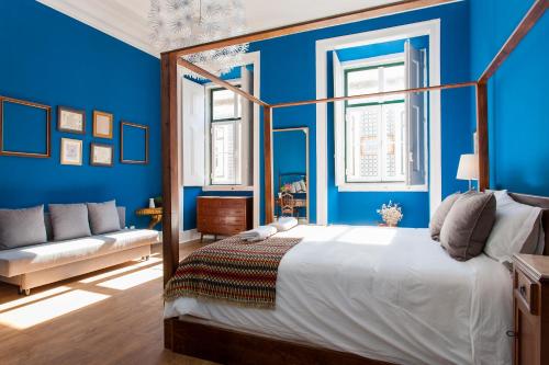 リスボンにあるSao Pedro de Alcantara 63 by Central Hill Apartmentsの青い壁のベッドルーム1室、ベッド1台、ソファが備わります。