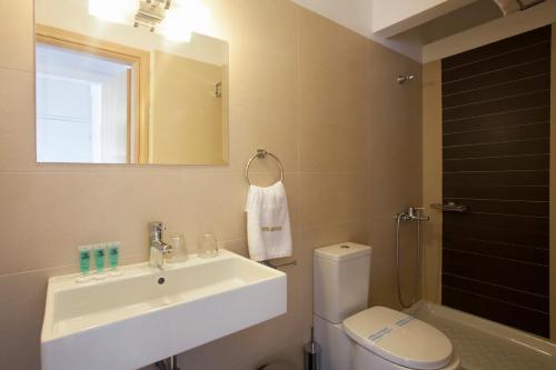 a bathroom with a sink and a toilet and a mirror at Metropolis Hotel in Athens