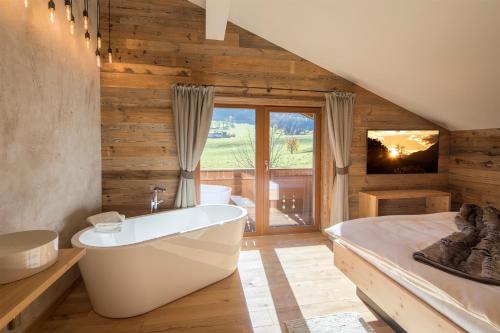 baño con bañera, cama y TV en Haus Sonnblick Penthouse, en Reith im Alpbachtal