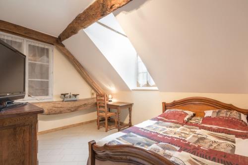 een slaapkamer met een bed, een tv en een raam bij L'Hirondelle in Lantilly