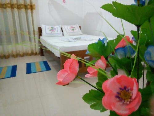 Una habitación de hospital con una cama y flores en primer plano. en Relax Homestay, en Tangalle
