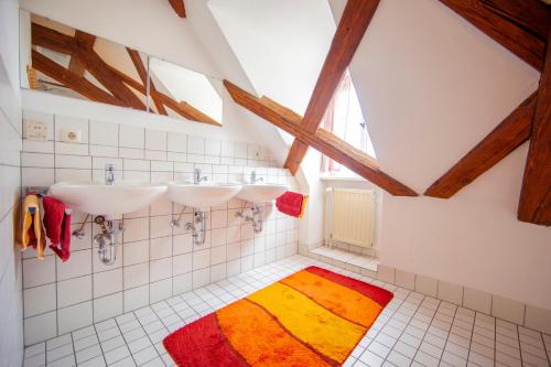 un bagno con tre lavandini e un tappeto colorato di Pension Pastoriushaus a Bad Windsheim