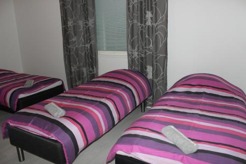 two beds sitting next to a window in a room at Majoituspalvelu Nurmi Apartment Oksapolku 2 B Deluxe Huoneisto 103m2 in Raahe