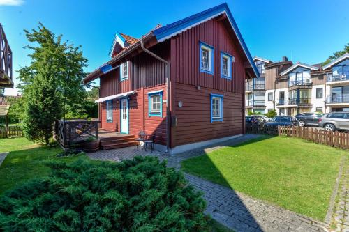 a red house with a yard in front of condos at Villa Erika in The Heart of Nida in Nida