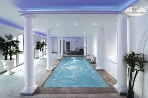 a large swimming pool in a mansion with a blue ceiling at Le Continental in Condom