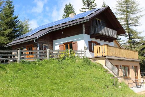 a house with a solar roof on top of a hill at Gartenwohnung auf der Sommeralm in Sankt Kathrein am Offenegg
