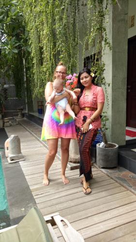 two women standing next to a pool with a baby at Pujihouse One in Legian