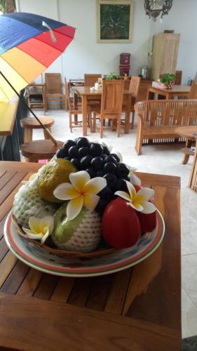 a plate of fruit on a table with an umbrella at Pujihouse One in Legian