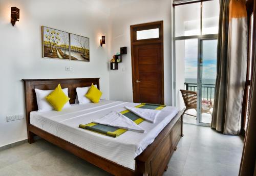a bedroom with a bed with yellow pillows and a window at Rominrich in Hikkaduwa